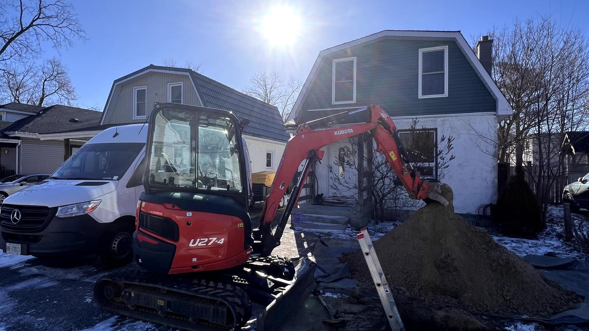 Mini excavator opening a residential lawn for a water service upgrade